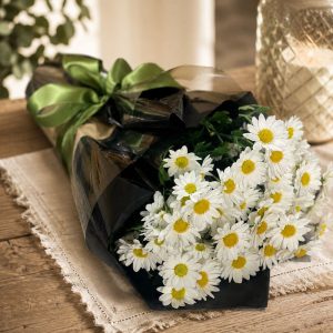 Buquê de mini margaridas brancas embalado em papel preto premium com laço verde